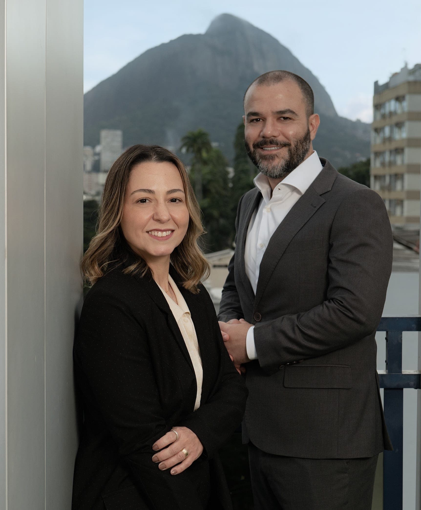 Advogados sócios em pose profissional com Pão de Açúcar ao fundo transmitindo parceria, confiança e expertise legal