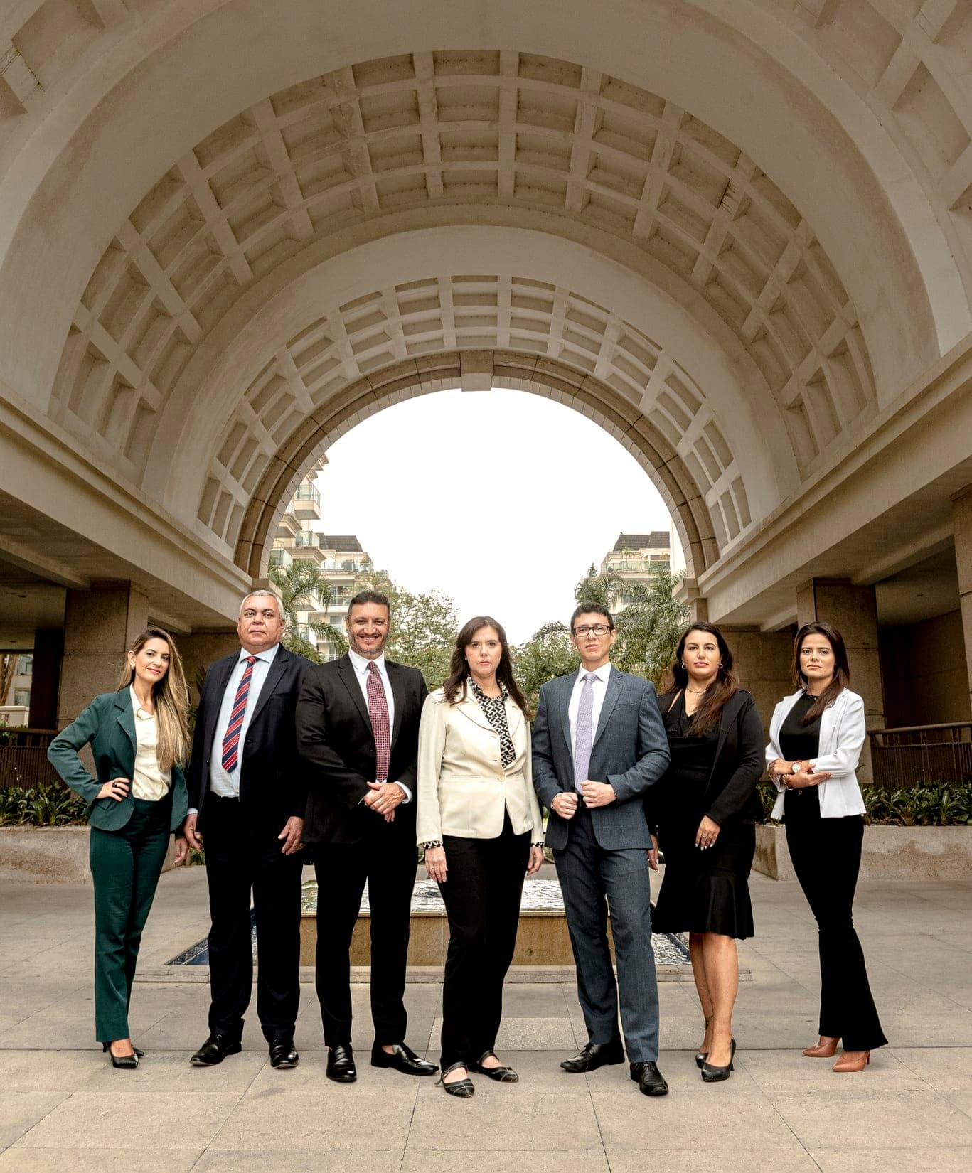 Equipe de sete advogados em ambiente arquitetônico transmitindo solidez, expertise coletiva e liderança profissional