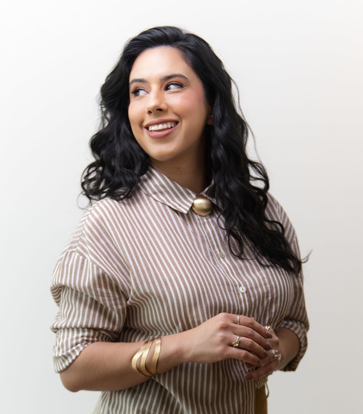 Mulher em sorriso contagiante olhando para o lado durante retrato de estúdio transmitindo confiança, naturalidade e carisma profissional