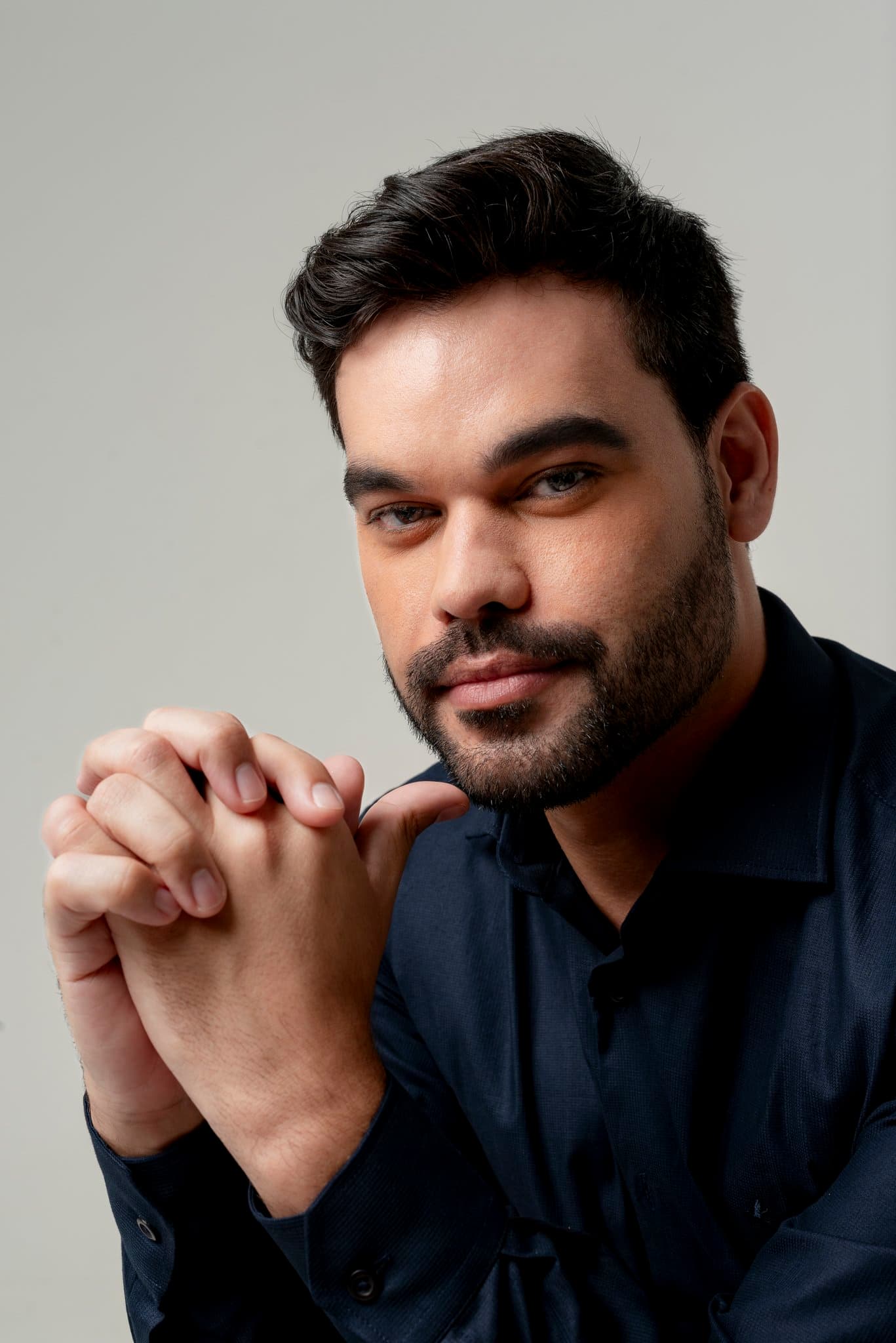 Retrato corporativo de homem de terno sorrindo com confiança, ensaio fotográfico Aura Estúdio em Barra da Tijuca, Rio de Janeiro