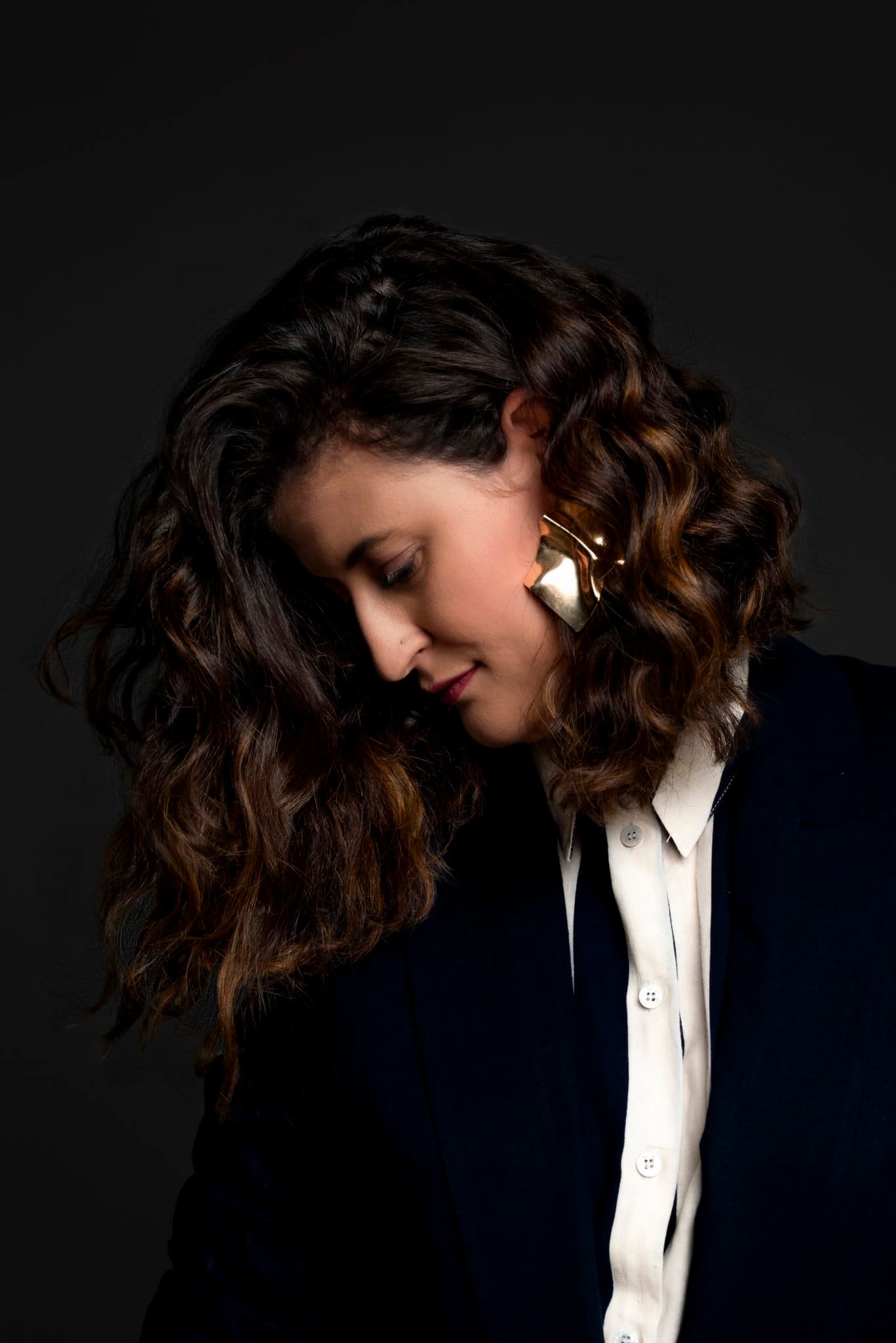 Retrato editorial corporativo de mulher de blazer em perfil, luz dramática, ensaio de posicionamento Aura Estúdio Rio de Janeiro