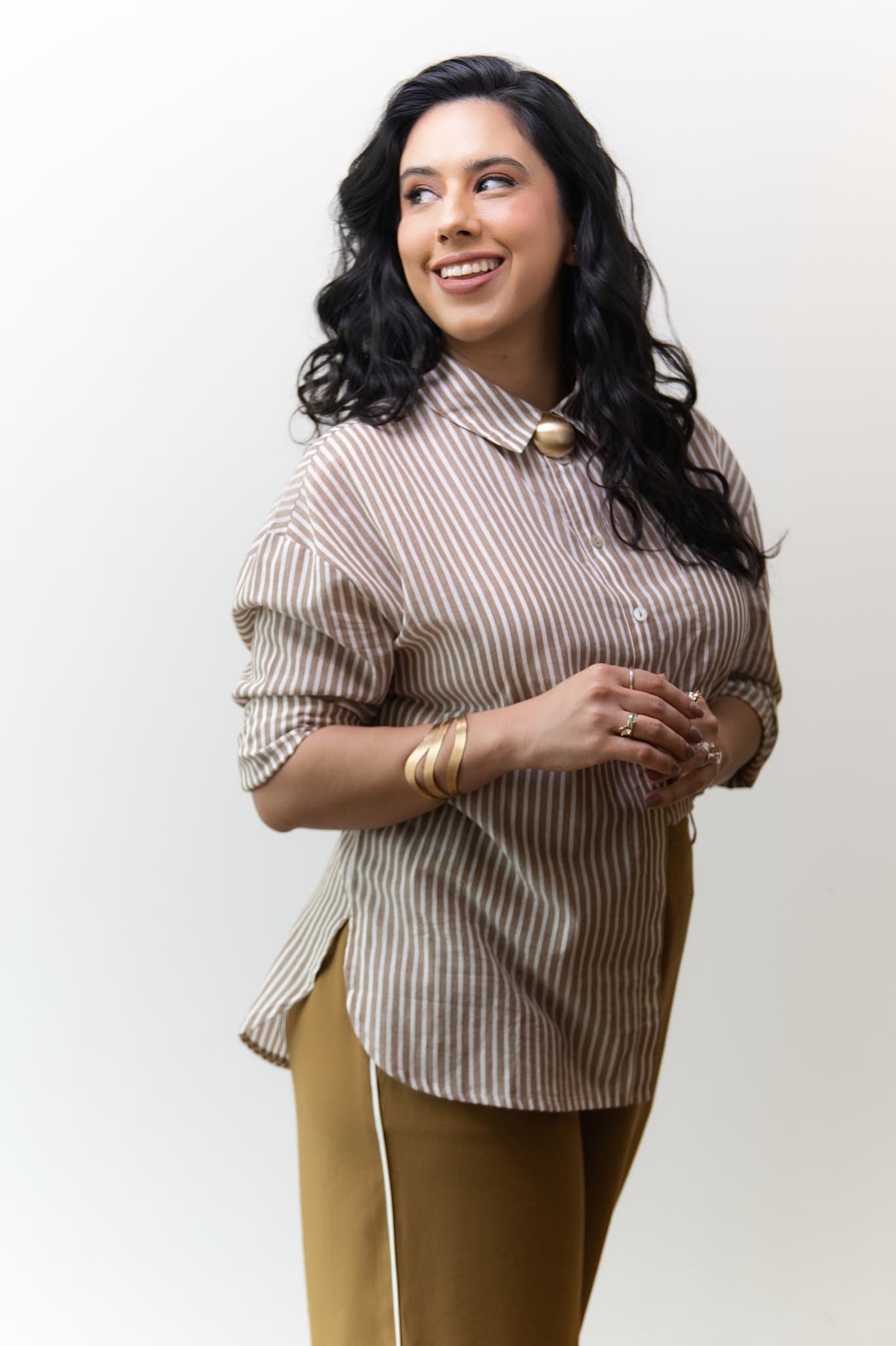 Mulher em sorriso contagiante olhando para o lado durante retrato de estúdio transmitindo confiança, naturalidade e carisma profissional