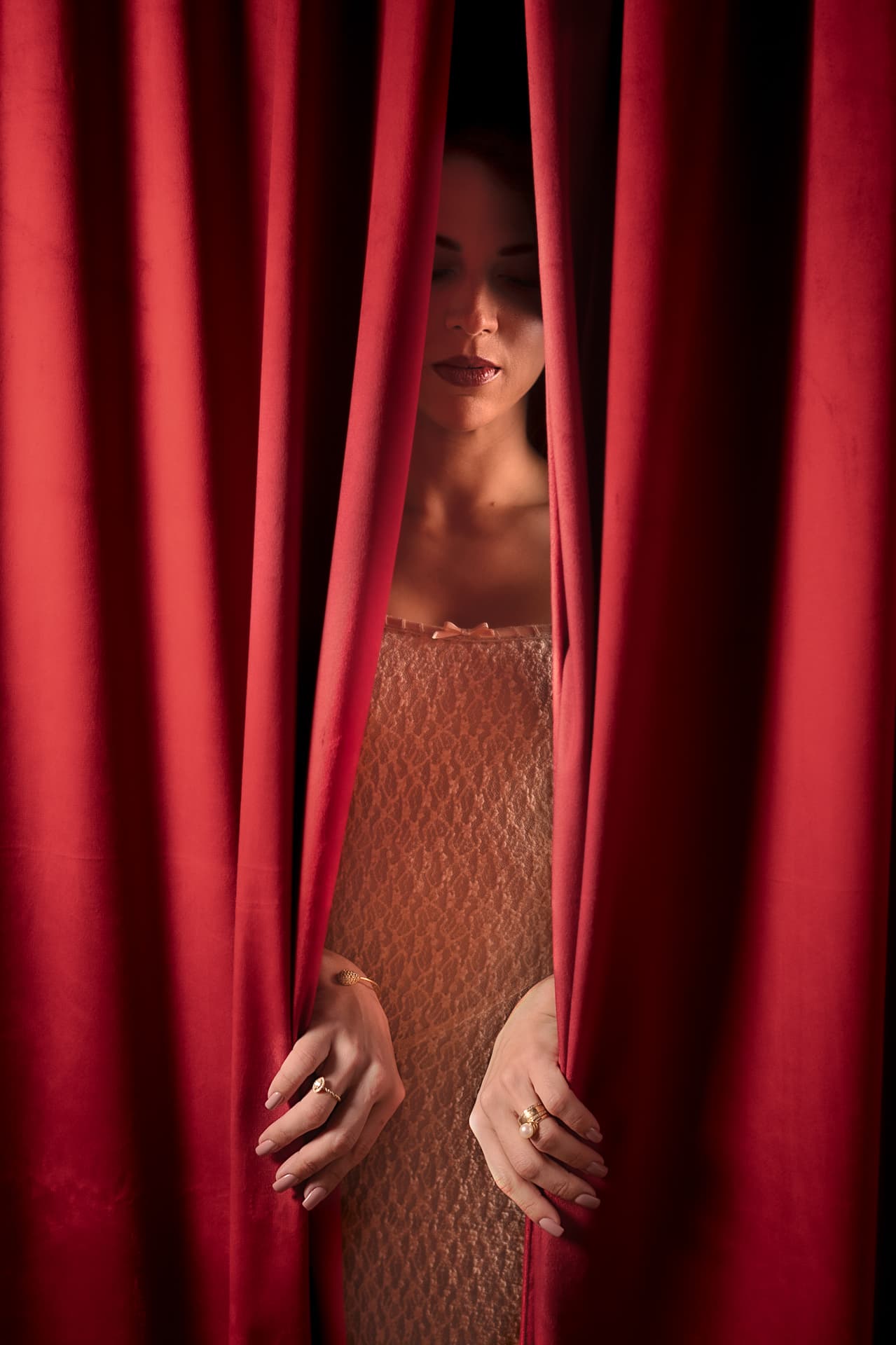 Retrato Ensaio Fascínio — mulher olhando por entre cortina vermelha, Aura Estúdio