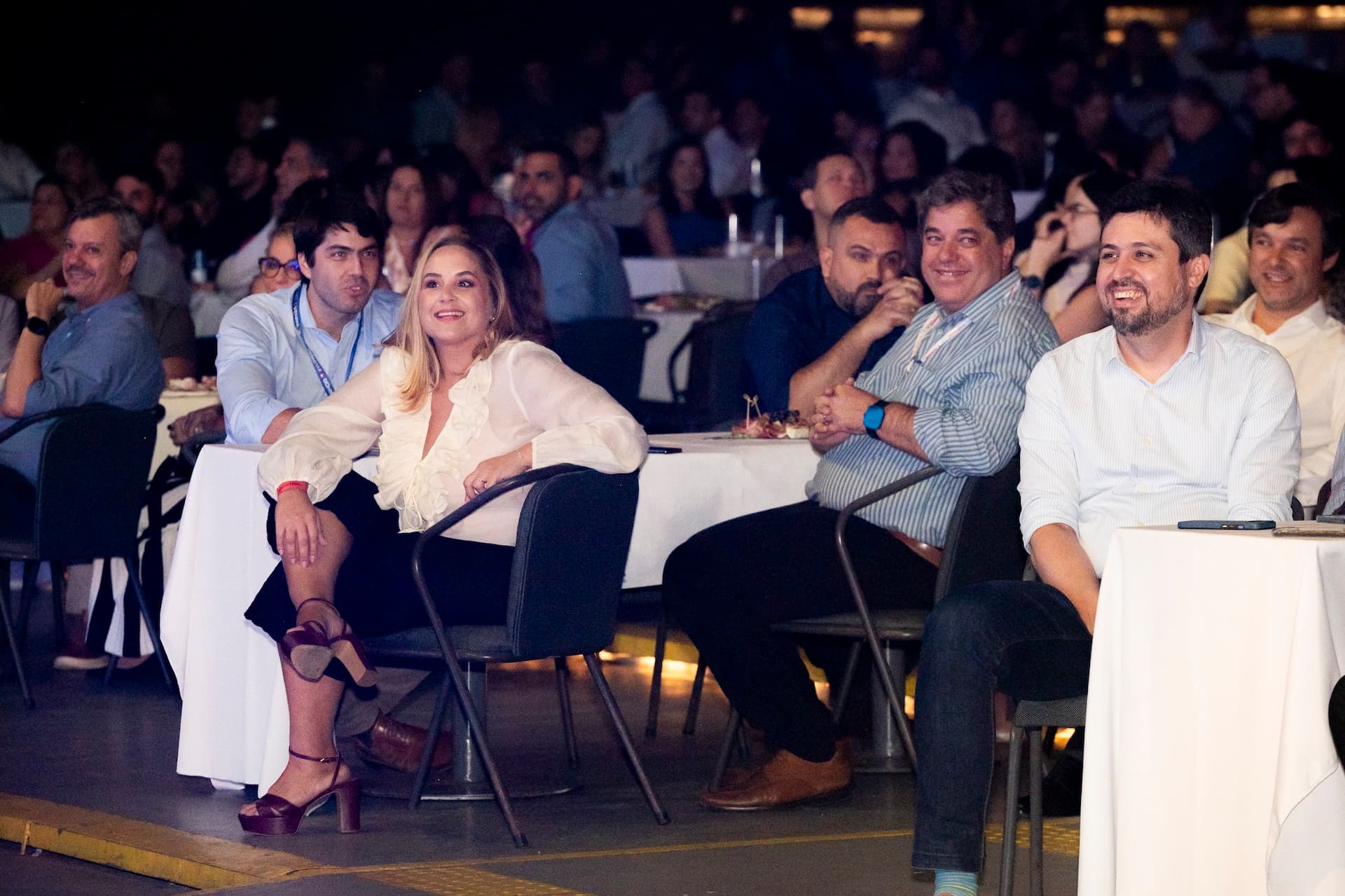 Plateia sorridente durante apresentação em convenção corporativa noturna