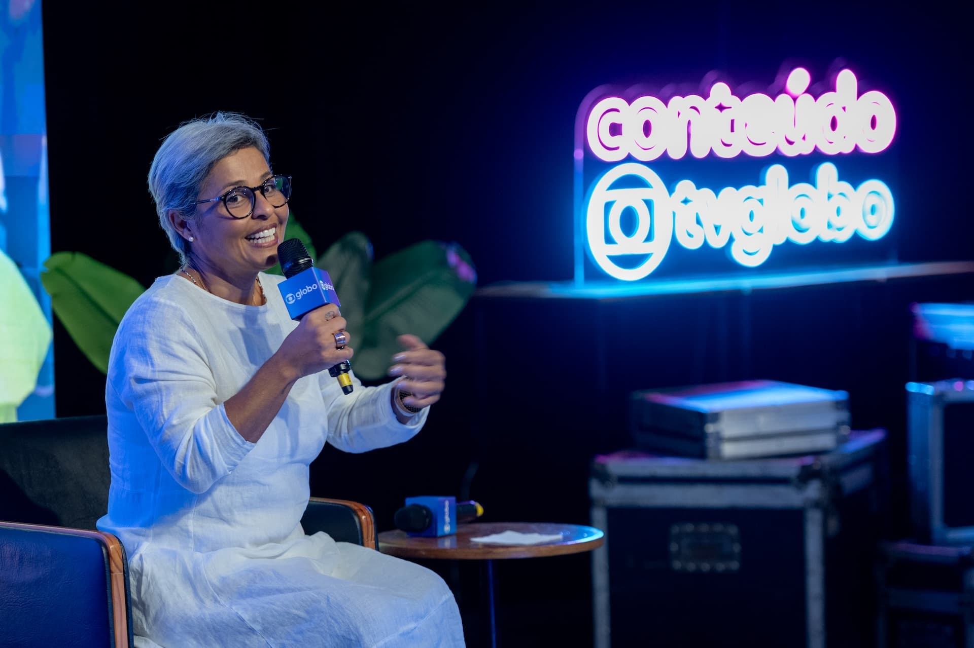 Palestrante em painel com neon "Conteúdo TV Globo" durante evento corporativo