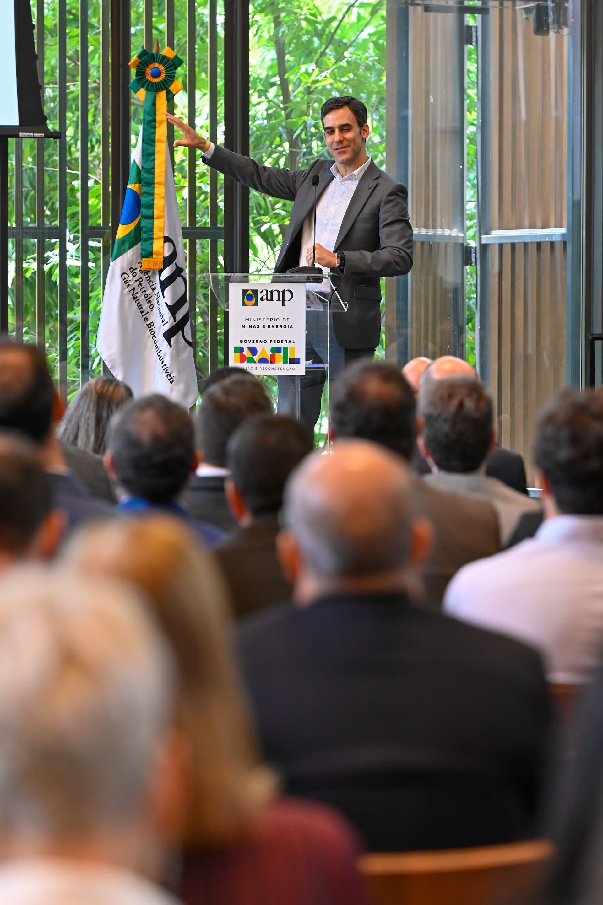 Palestrante discursando ao lado da bandeira do Brasil em cerimônia de premiação da ANP