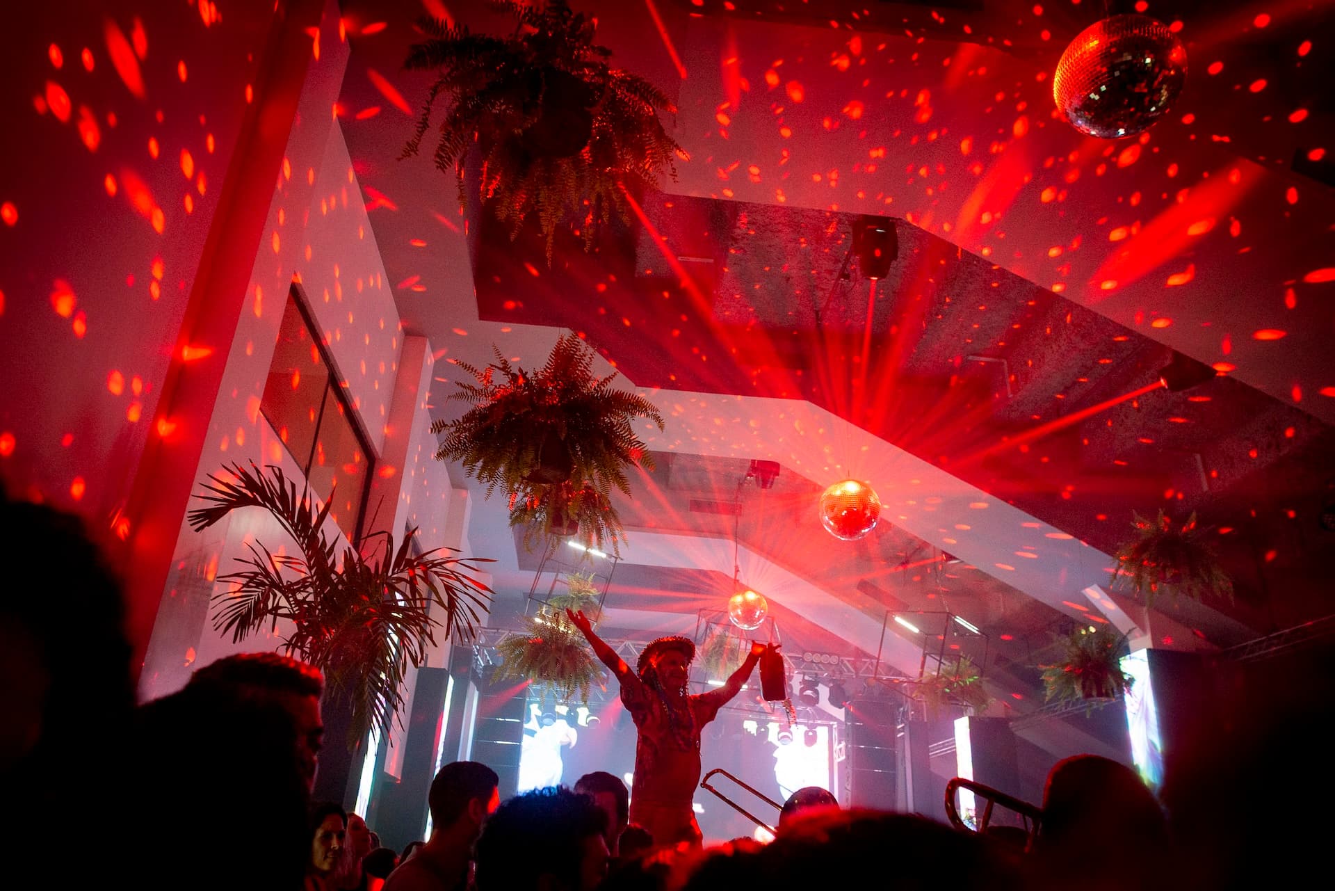 Multidão dançando em balada corporativa com luzes roxas e azuis