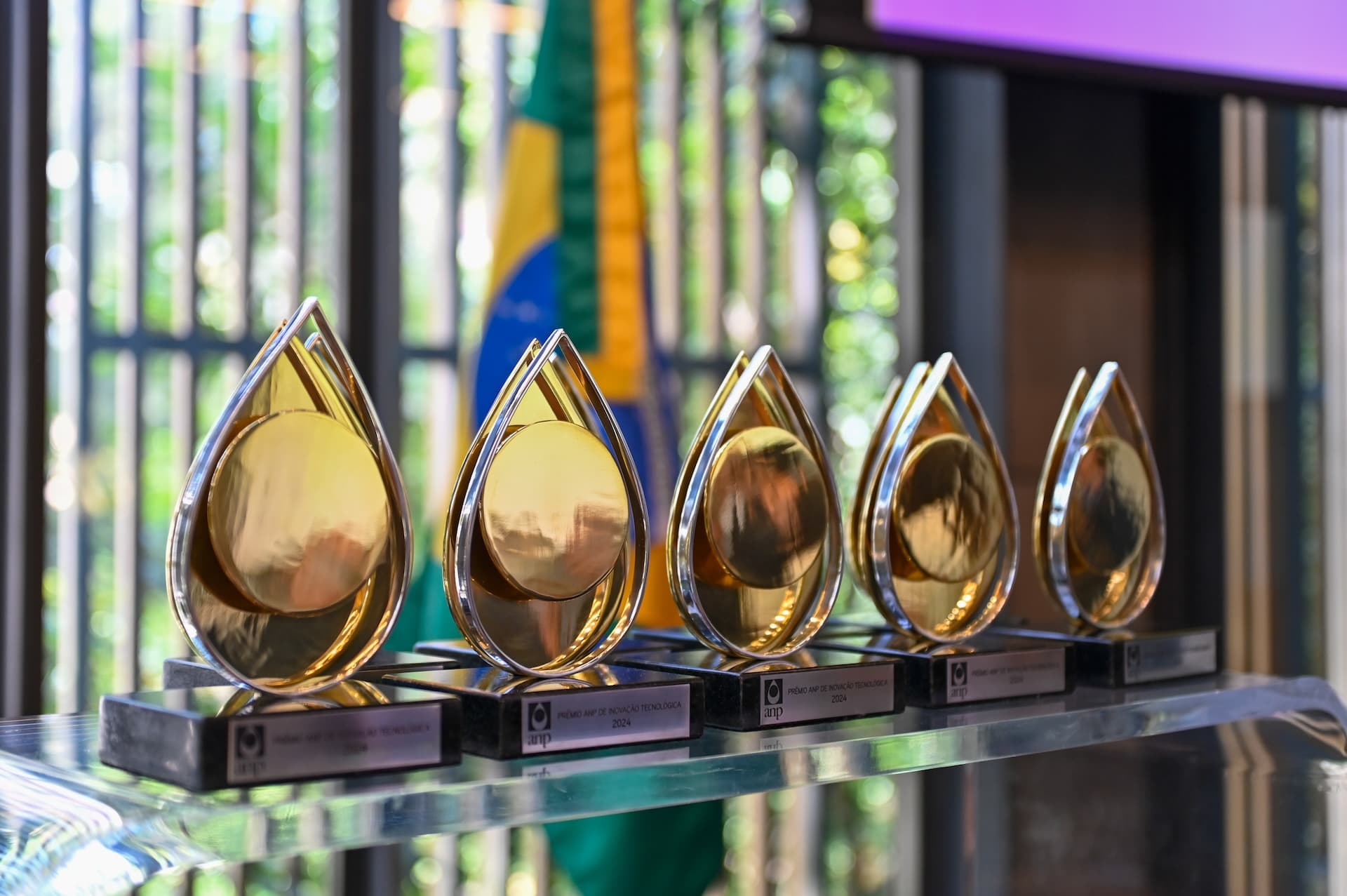 Troféus dourados em formato de gota do Prêmio ANP de Inovação Tecnológica expostos em mesa